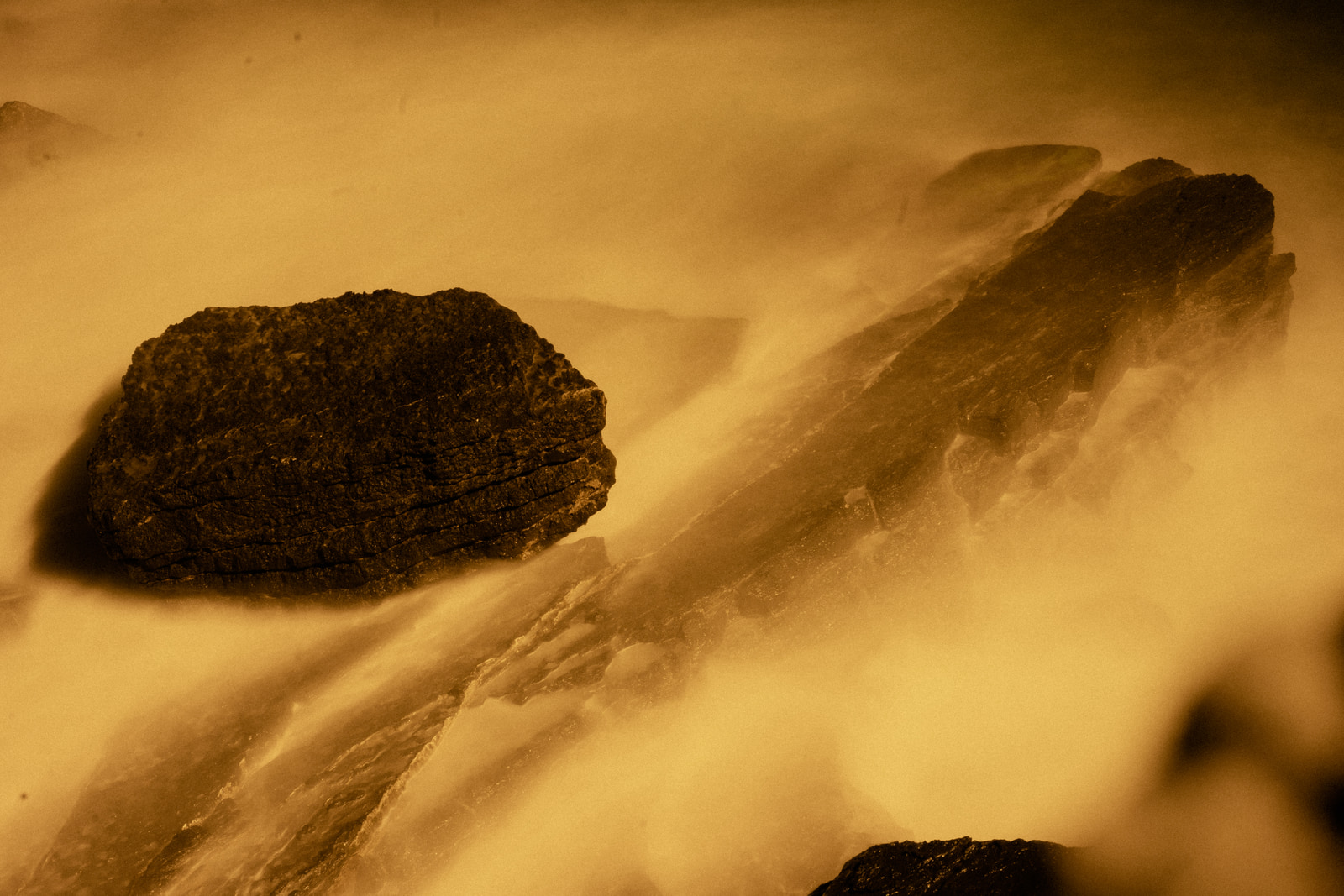 Dark, angular rock fragments rest against a warm-toned, misty background.