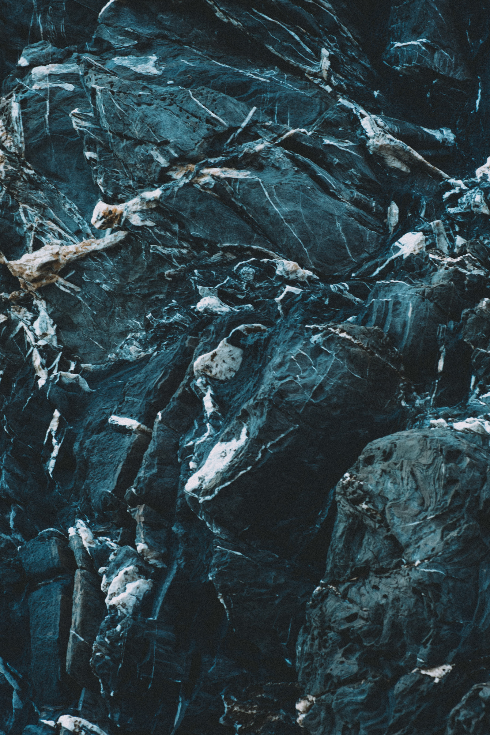 Close-up view of dark, textured rock formations with visible mineral veins and striations.