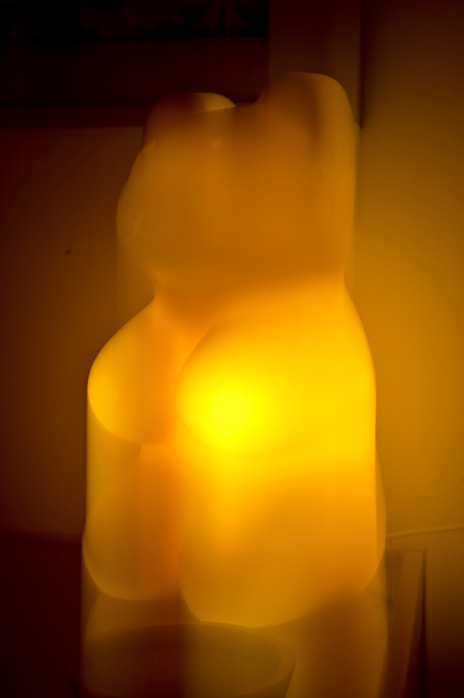 A glowing, abstract sculpture with soft, rounded forms and a warm yellow light emanating from its center.
