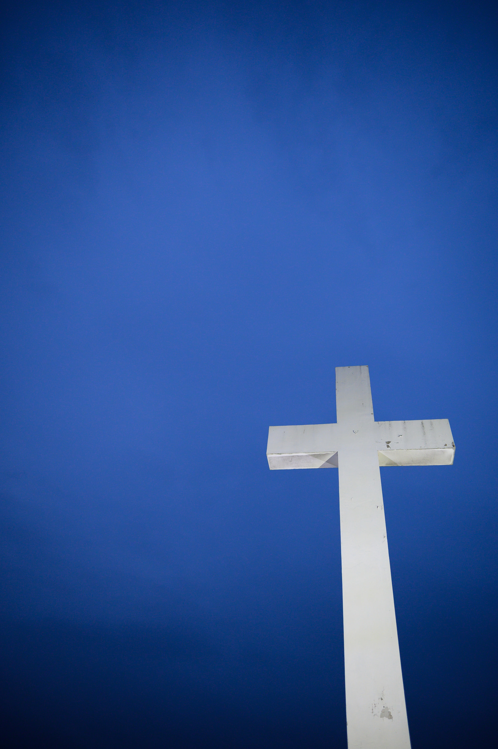A white cross stands tall against a deep blue sky.